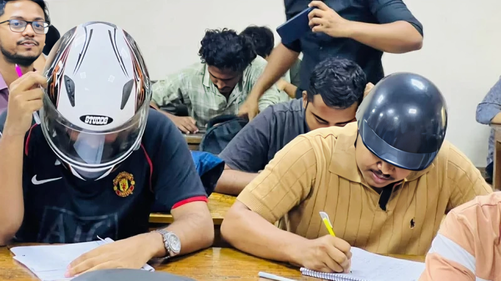 নিরাপত্তার জন্য হেলমেট পড়ে পরীক্ষা দিচ্ছেন শিক্ষার্থীরা